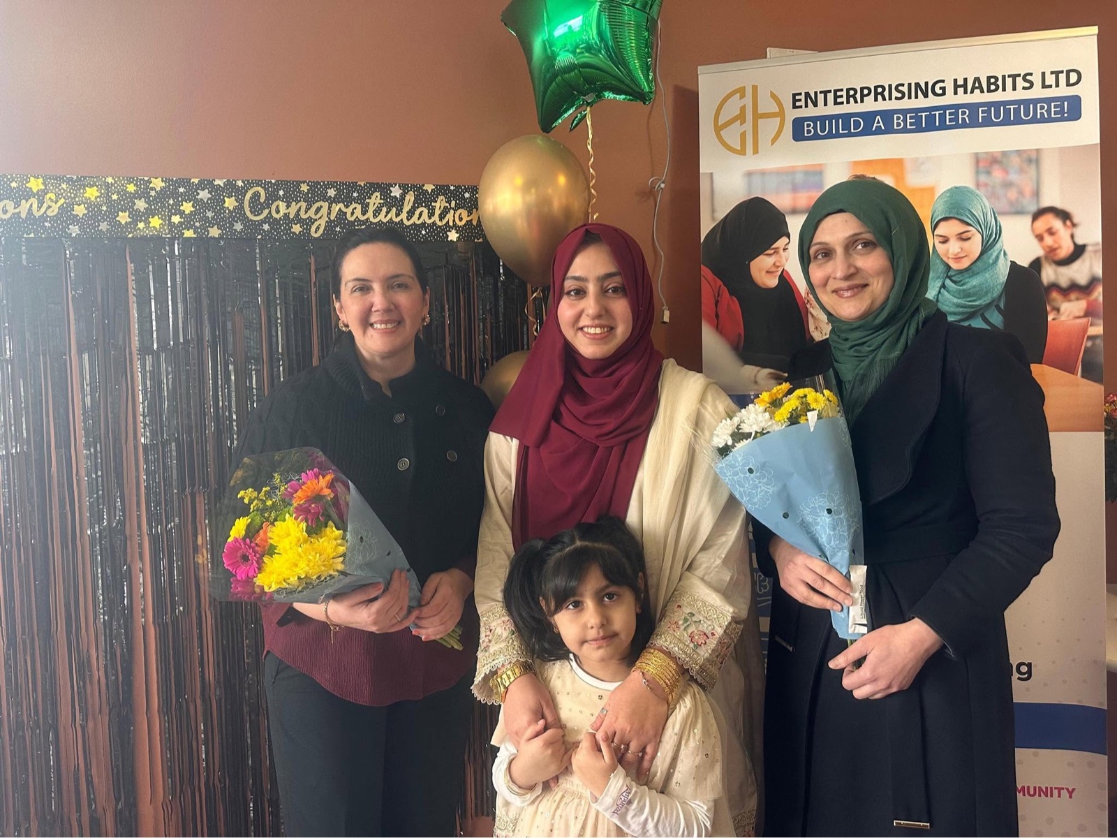 Community members celebrating with flowers beside an Enterprising Habits banner.